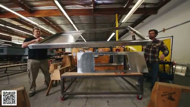 Two workers checking the fit of raw aluminum camper components