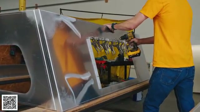 A worker measuring the raw aluminum camper assembly